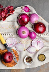 Composition of fresh raw onion and spices on gray background