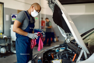 African American car mechanic wearing protective face mask while working in a workshop.