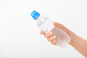 Female hand and bottle of water on white background