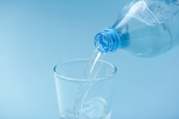 Pouring of water into glass on color background