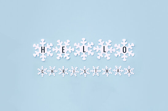 Words Нello Сhristmas on decorative white snowflakes on blue background. Minimal winter or New Year composition.
