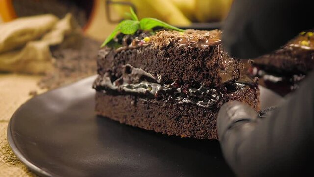 Professional chef puts the chocolate slice cake on the plate. Close up. Slow motion.