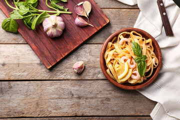 Plate of tasty pasta with shrimps and garlic on wooden table