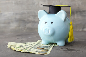 Piggy bank with graduation hat and money on table