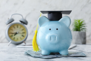 Piggy bank with graduation hat and money on table