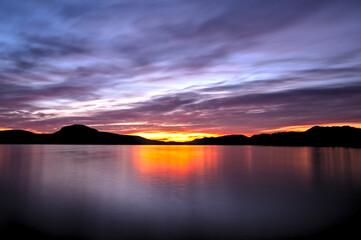 Fototapeta na wymiar 雲の広がる美しい空。太陽の光にオレンジ色に染まる湖。