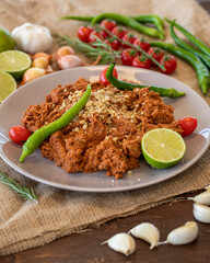 Muhammara, healthy walnut and roasted red bell pepper dip served with flatbread in a ceramic bowl