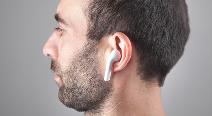 Caucasian man wearing white wireless earphone.