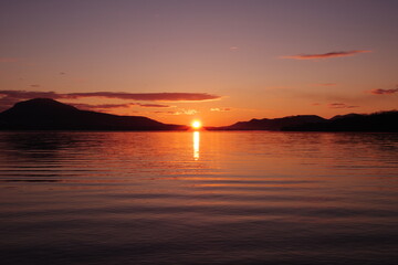 太陽の光に紅く染まる湖の風景。陽光の下のカルデラ湖の明媚な瞬間。