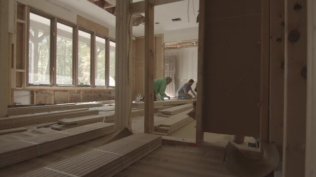 Construction workers begin to lay hardwood floors