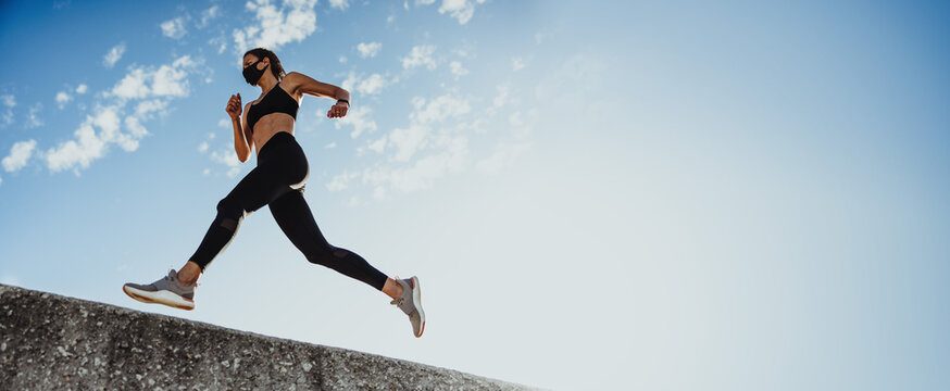 Panoramic shot of sports woman running over wall