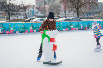 In winter, on the rink, a boy learns to skate.