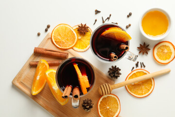 Cups of mulled wine and ingredients on white background