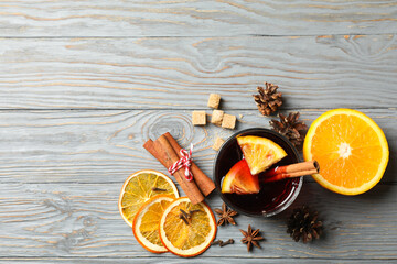 Glass of mulled wine and ingredients on gray wooden table