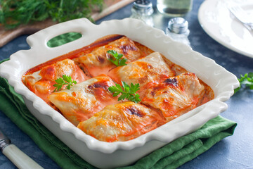 Cabbage rolls with minced meat and rice baked in the oven on the table in a ceramic form, horizontal