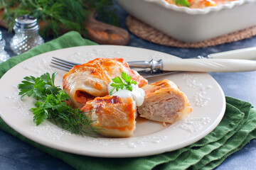 Cabbage rolls with minced meat and rice on a plate with sour cream and herbs, selective focus