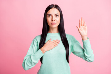 Photo portrait of serious woman taking an oath showing one palm hand on chest isolated on pastel pink colored background