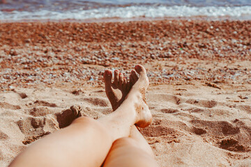 women's feet on the beach by the sea