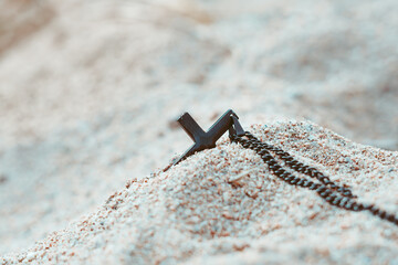 a cross with a chain lies in the sand