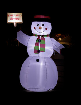 Blow-up Snowman with hat and scarf decorations glowing in the dark and wishing Merry Christmas.