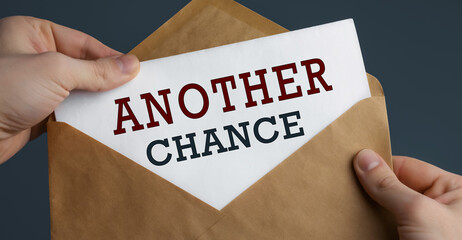 Male hands holding craft envelope with text ANOTHER CHANCE on blue background