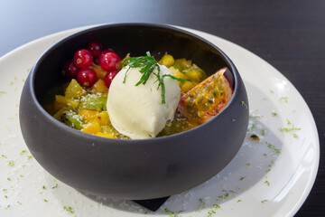 Fruit salad with ice cream in a black bowl at a restaurant