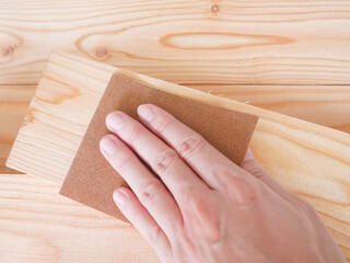 Hand sanding wooden pallet with sandpaper
