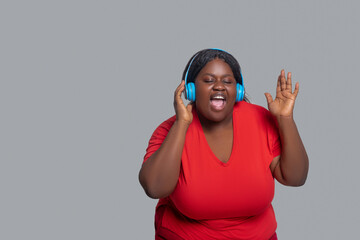 Young dark-skinned woman with headphones looking excited