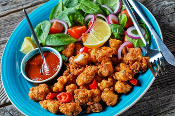 Popcorn chicken with ketchup and salad, close-up