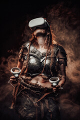 Weared with virtual reality glasses scandinavian woman warrior in light armour poses in atmospheric smokey background.