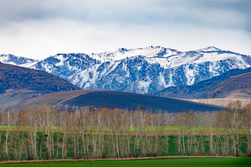 autumn picturesque green valley, with foothills covered with snow, sky in the background with dark clouds