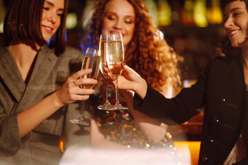 Three young Woman with champagne glasses at night club.  Women friends drinking champagne  in the bar. Party, celebration, friends, bachelorette party, birthday, winter holidays concept.