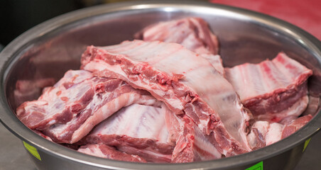 Lots of fresh pork ribs in a large iron bowl