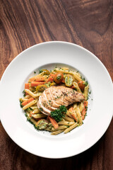 fried chicken breast with penne and saute vegetables pasta dish