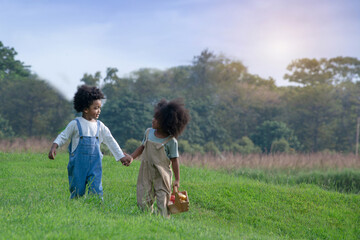 Two dark-skinned boy and girl held hands and walked together on a beautiful lawn, spending time together outside in nature