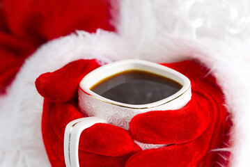Obraz na płótnie Canvas Santa claus holding white mug with coffee in his hand, close-up.