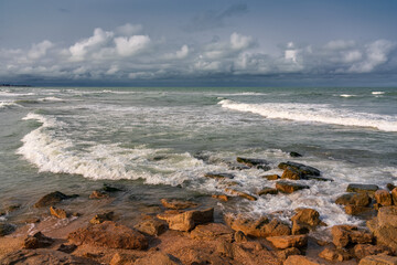 Fototapeta na wymiar Empty rocky beach and stormy sea in cloudy weather