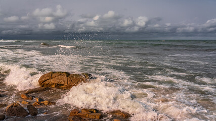 Empty rocky beach and stormy sea in cloudy weather