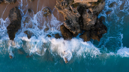 Aerial view of waves breaking against the rocks of cliffs in a Spanish beach in Cadiz