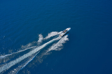 Aerial view of a boat in motion on blue water. Top view of a white boat sailing in the blue sea. luxury motor boat. Drone view of a boat sailing at high speed.