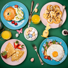 Easter breakfast flat lay with scrambled eggs bagels, tulips, pancakes, bread toast with fried egg and green asparagus, colored quail eggs and spring holidays decorations. Top view.