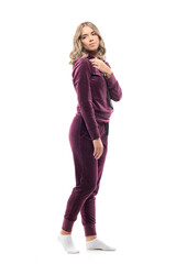 Fototapeta premium Side view of cute feminine young beauty woman in comfy sweatsuit looking back touching shoulder. Full body length isolated on white background. 