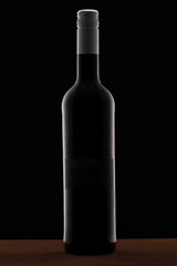 Red wine bottle isolated in a dark and elegant studio shot.