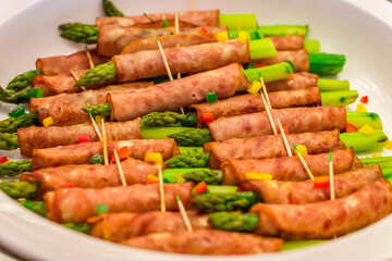 a buffet offering of asparagus wrapped in ham and skwered with a toothpick