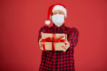 Man in protective face mask and Santa hat with Christmas DIY gift