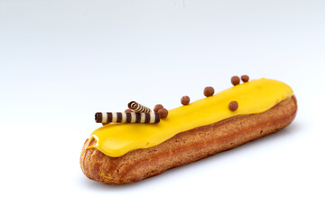 Eclair with custard and lemon glaze on a white background. Confectionery for the sweet tooth.