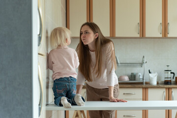 Mom is angry at little child standing in the kitchen