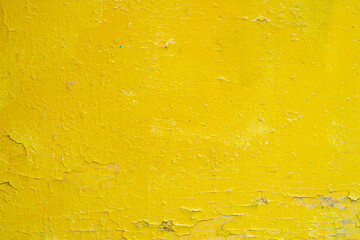 Background with a surface painted with bright yellow paint. Cracked old paint on a wooden surface