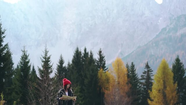 Young asian girl lost on route hiking trail during trekking with map in hands. Woman reading map and looking for trail in nature. Outdoor activities on weekends or holidays. Travel, adventure concept.