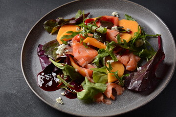 Fresh salad with salmon, persimmon, arugula and cashew. Served with pomegranate honey sauce